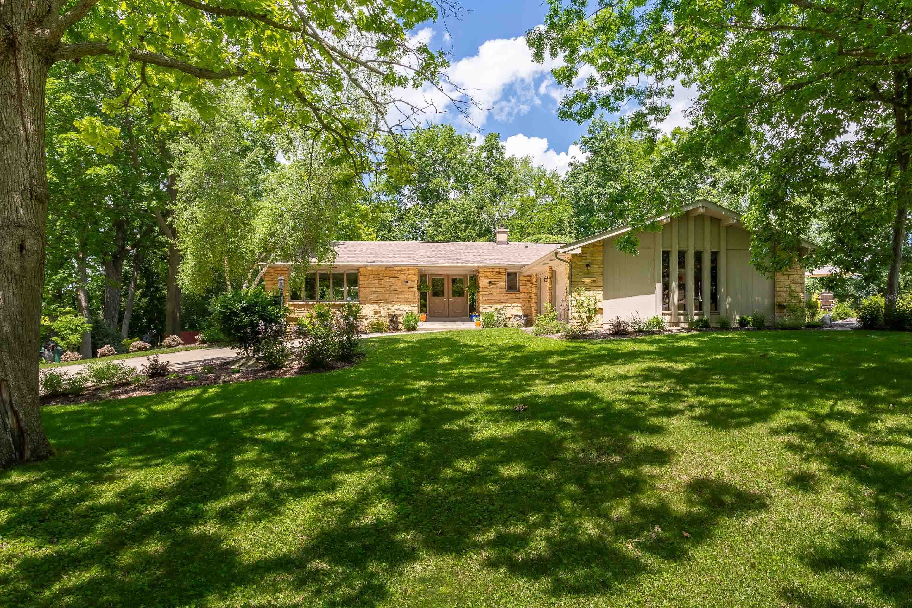 You'll love this sprawling ranch on a gorgeous, beautifully landscaped, wooded lot close to Token Creek Park.  Updated in 2019, this home features plenty of light-filled living space. Just off the airy entry is the spacious living room with built-ins, a floor-to-ceiling fireplace, gorgeous wood floors that run throughout the main living areas & sliding doors to the deck. This flows into the bright kitchen with timeless finishes & a convenient breakfast bar. The dinette opens to the deck - an ideal spot for an al fresco meal. Two bedrooms on the main level include the primary suite w/WIC. A lower level rec room includes a second fireplace, an office, a 3rd bedroom, an exercise or hobby room, & storage. Main floor laundry. Enjoy convenient access to the airport.