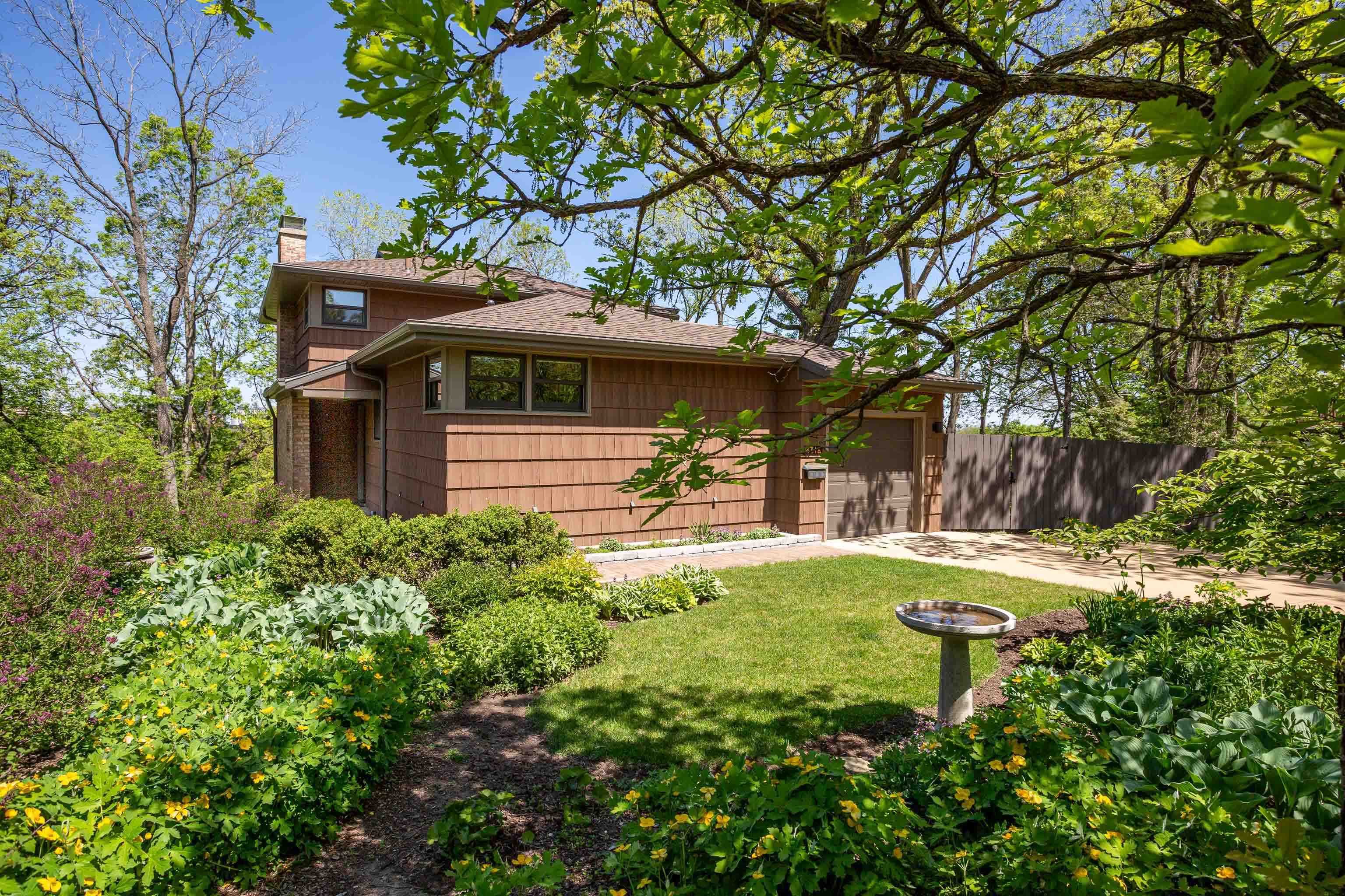 Nestled atop a wooded hillside, this serene home feels like a private treehouse retreat. Walls of windows bathe the main rooms in natural light, showcasing tranquil treetop views from the spacious living & dining rooms. A thoughtfully designed kitchen with tile backsplash complements the warmth felt throughout the house. Relax on the fantastic screened porch or entertain on the covered patio overlooking wildflower-filled woods, or in front of the living room fireplace on chilly nights. The primary bedroom, w/built-ins, is in its own area of the house next to a full bath. Two bedrooms share a full bath on the upper level. The LL has two versatile finished rooms that open to the covered patio. Enjoy privacy + an unbeatable location near Hilldale, parks, UW Hospital, & downtown Madison.