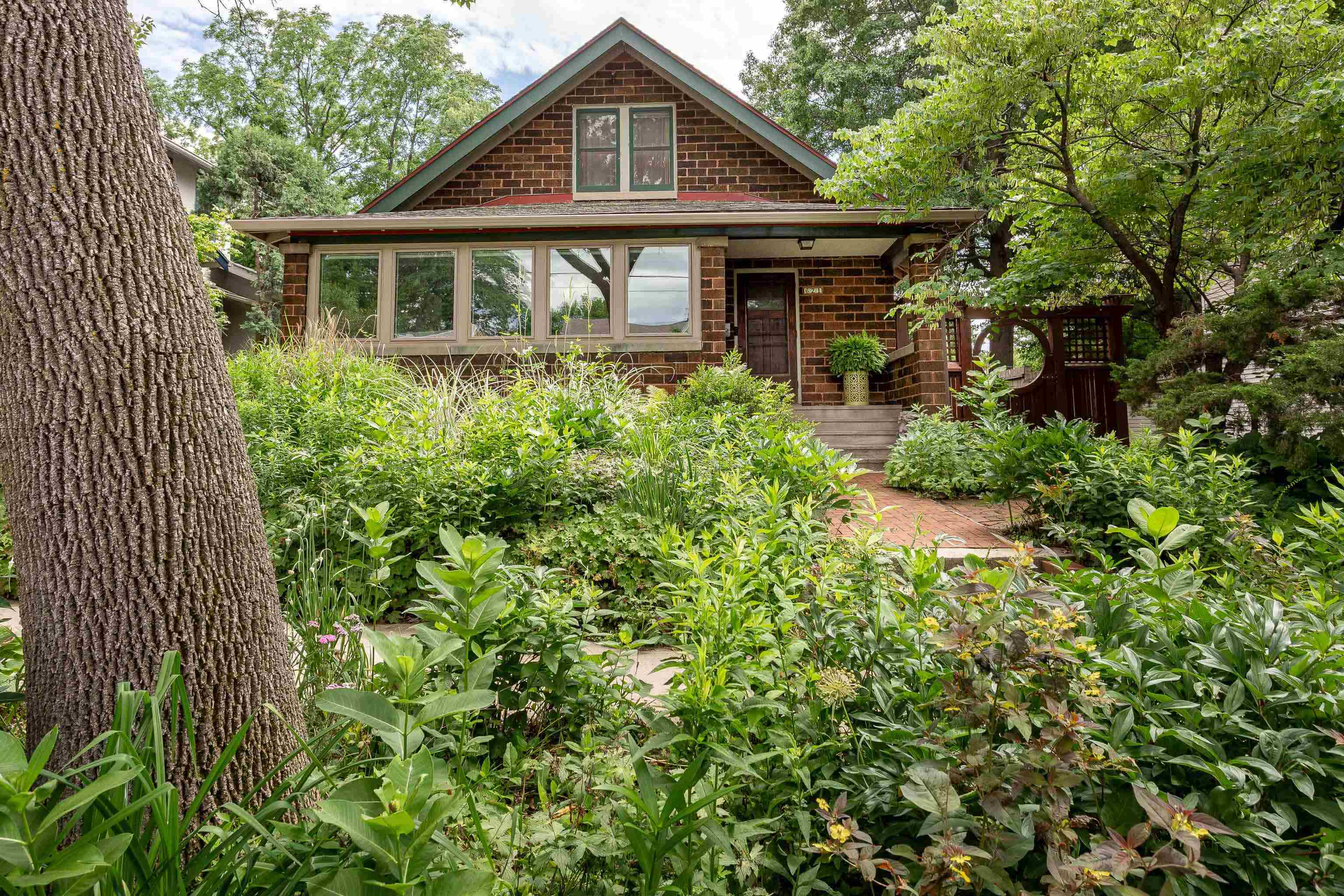 This charming 1920s brick bungalow in the heart of Bay Creek blends vintage character with modern comforts. Set in a lush yard bursting with unique & native plantings, you'll enjoy the custom arbor, brick patio, & pathways that meander through the gardens. After a lovely day outside, relax with friends in the sunroom that opens to the beautiful living & dining rooms with original wood flooring, or make a meal in the thoughtfully remodeled kitchen. Ideal for hobbyists, with a large lower-level workspace. Original woodwork and tiles throughout evoke timeless elegance.  Walk to the UW, downtown, Olin Park, the Arboretum, Monroe Street, schools, & the beach. A perfect mix of comfort, convenience, & charm!